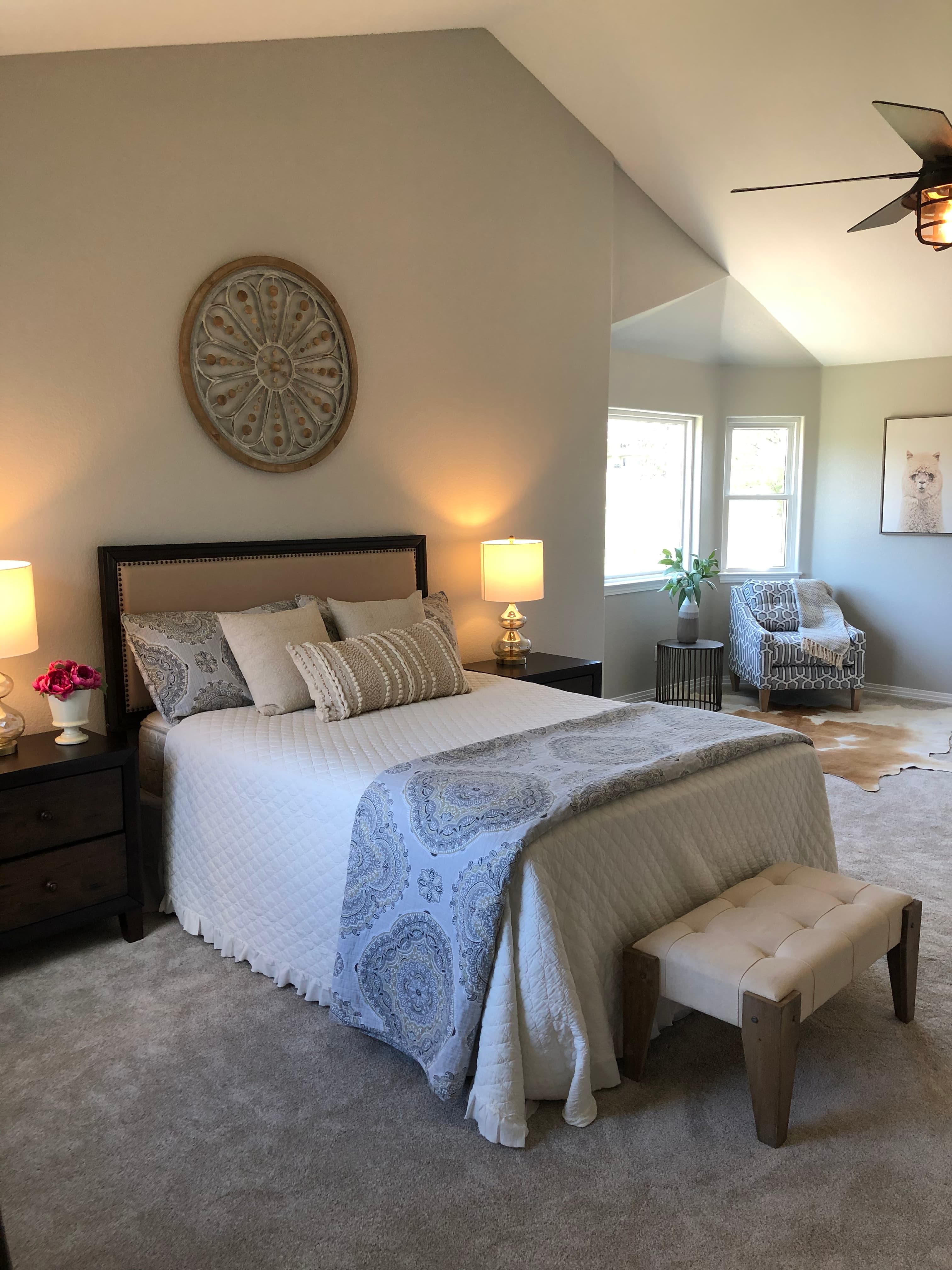 Staged bedroom with a white quilted bed, dark wood nightstands and gold lamps