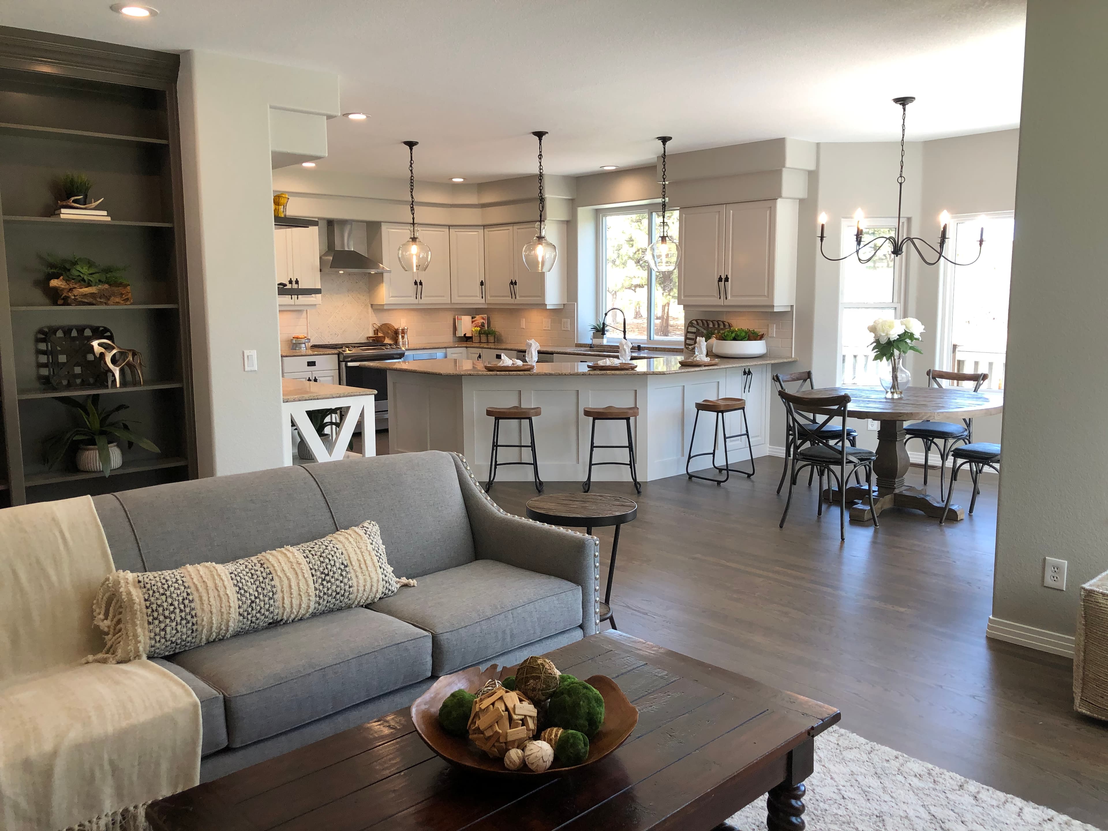 Open kitchen, dining and living room with a grey sofa and pendant lights